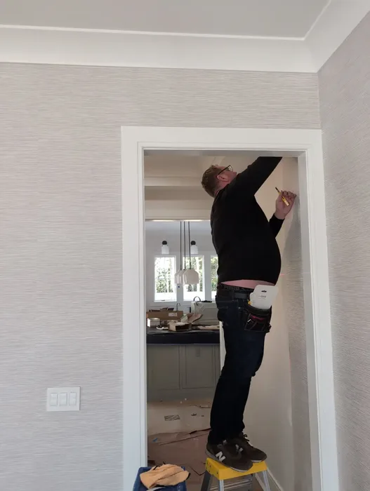 Wallpaper installer carefully aligning a premium wall covering in a Providence residence